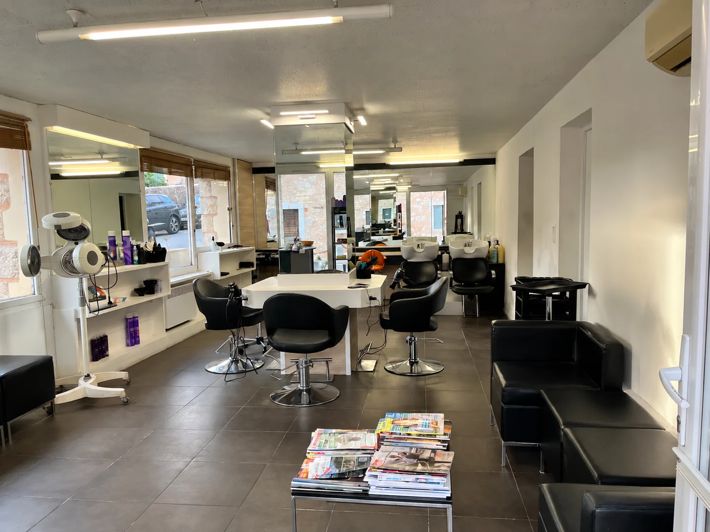 Vue d’ensemble du salon avec les miroirs, les fauteuils de coiffage et le coin attente